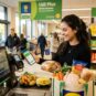 Estudante usando aplicativo de desconto no caixa de supermercado na Irlanda para economizar nas compras semanais.